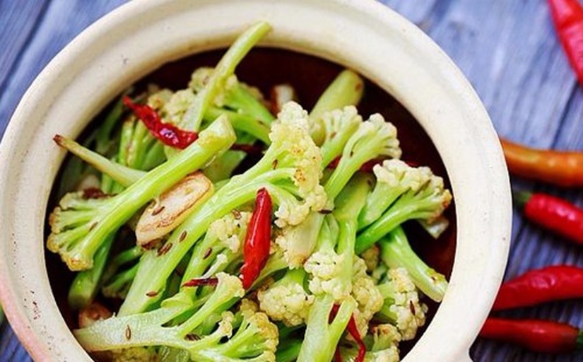 西兰花炒制过程特写：铁锅中翠绿西兰花与金黄蒜末同炒，油光亮泽，花球饱满未蔫塌