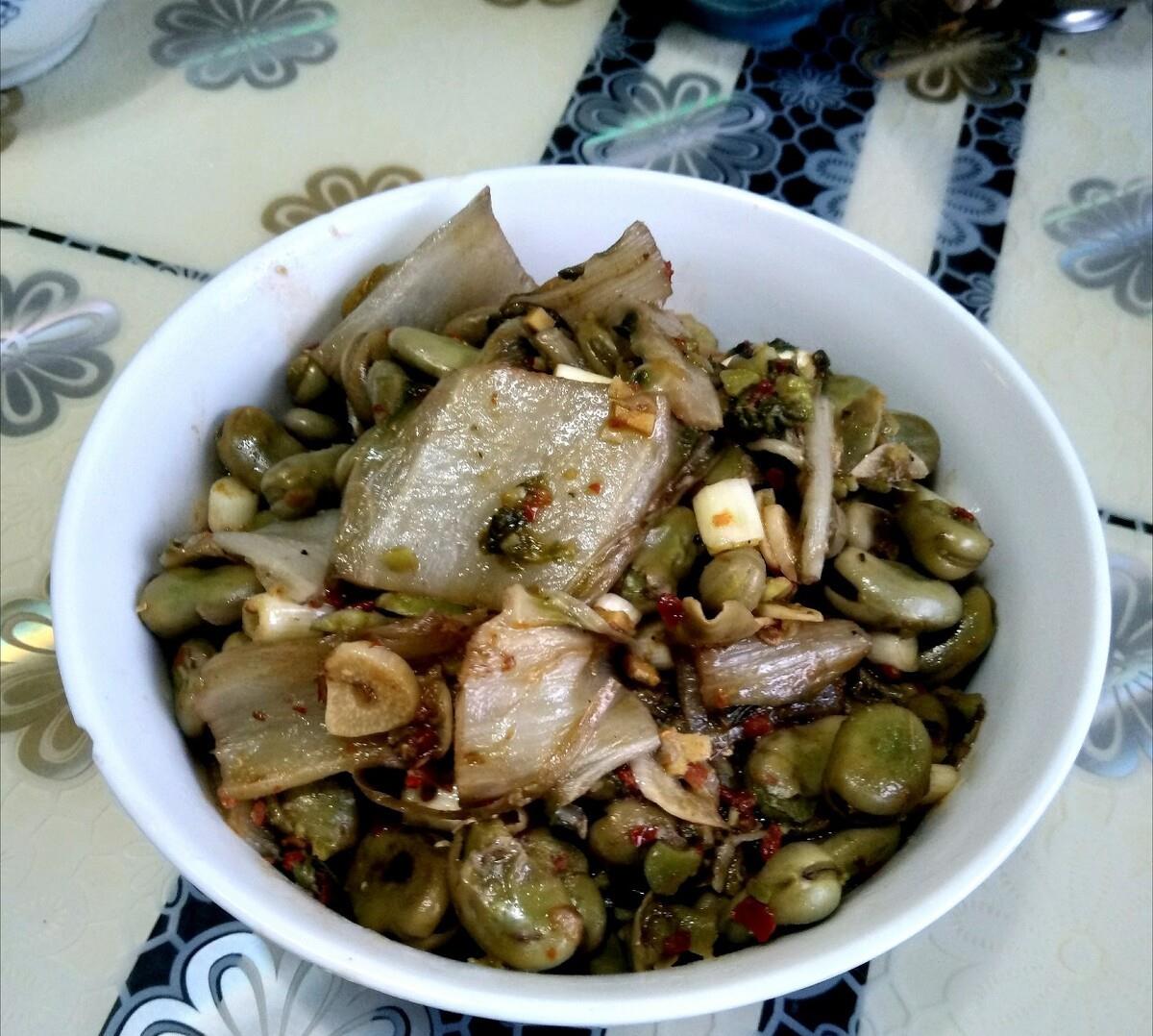 高清俯拍:青翠蚕豆粒与嫩绿丝瓜块分明交错,油润光亮不反光,可见完整豆粒轮廓与丝瓜纤维纹理;盘底无汁水残留,撒有零星白胡椒粉与细蒜末,背景为原木砧板与青瓷圆盘,呈现家常高级感 成品蚕豆丝瓜炒菜特写