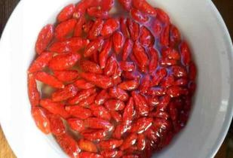 红枸杞正在清水中清洗与浸泡,旁边放置着清水碗和枸杞 红枸杞清洗与浸泡过程