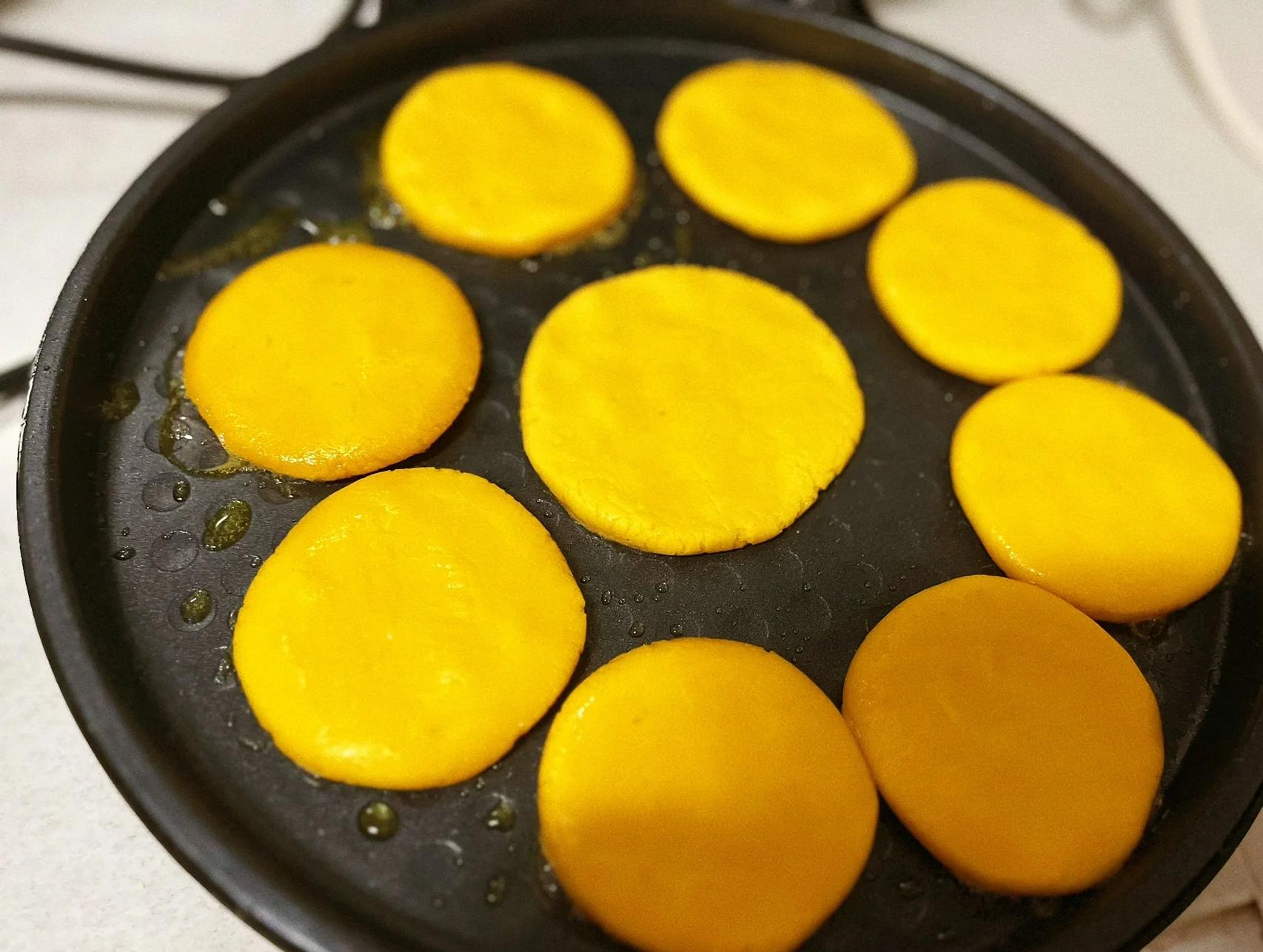 正在煎制的脆柿子饼,锅中油光发亮,饼面呈现金黄色 煎制脆柿子饼过程展示