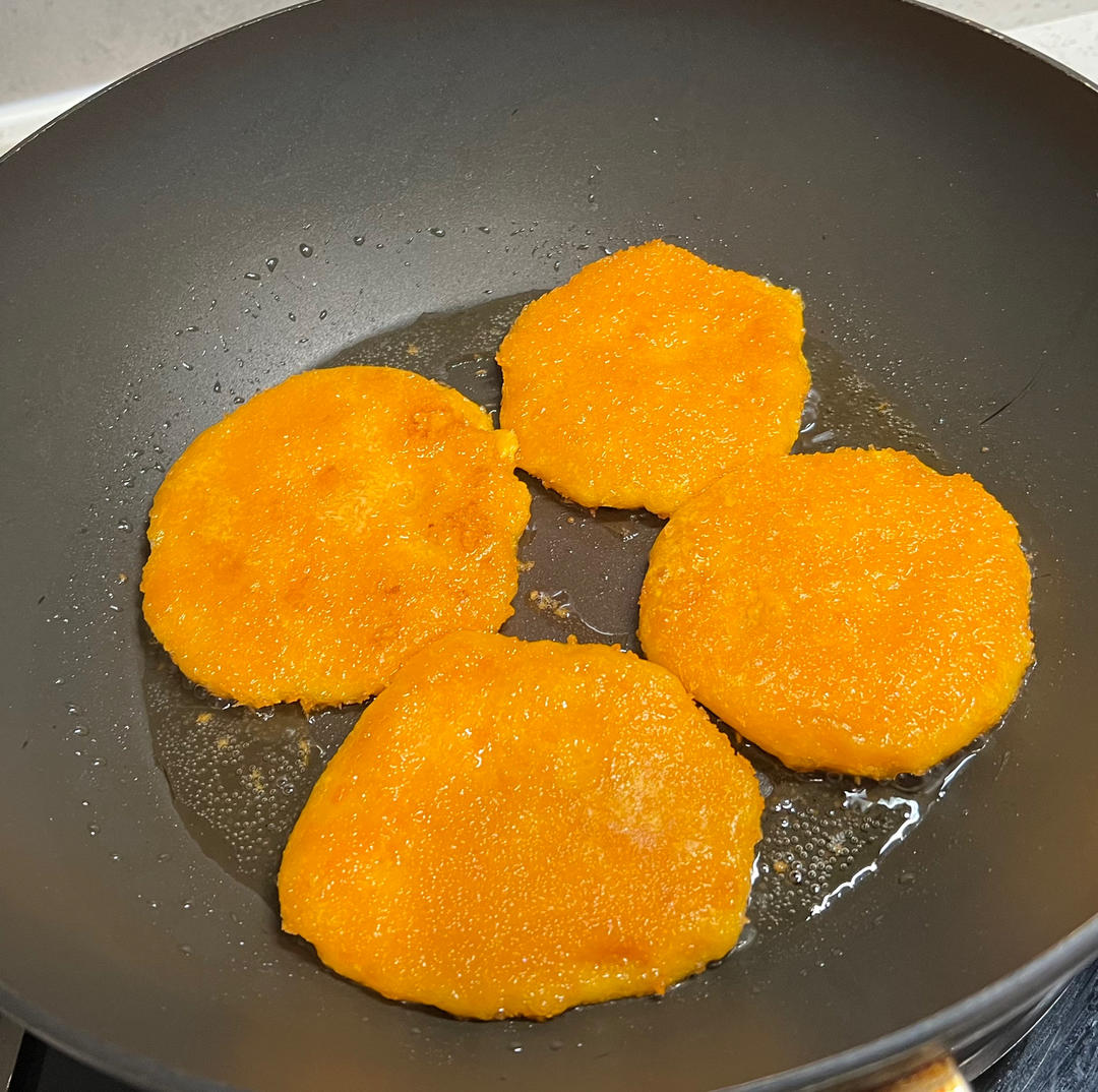 家庭厨房中正在煎制蜜本南瓜饼的场景