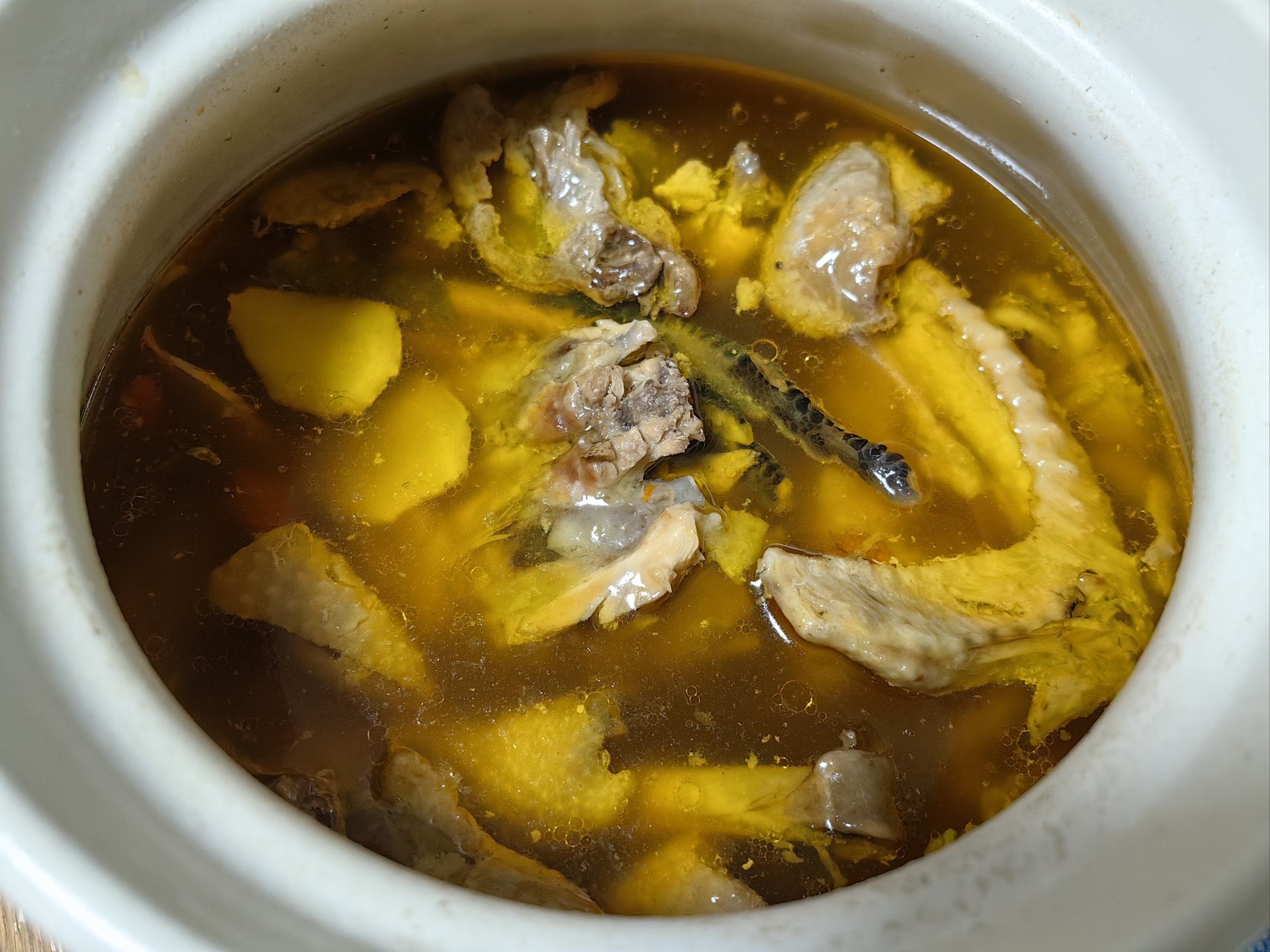 砂锅中正在炖煮的鸡腿汤,汤色呈乳白色,锅边可见微微沸腾,上方飘着姜片和葱段,旁边放着切好的白萝卜块,展现炖煮中期状态 炖煮过程