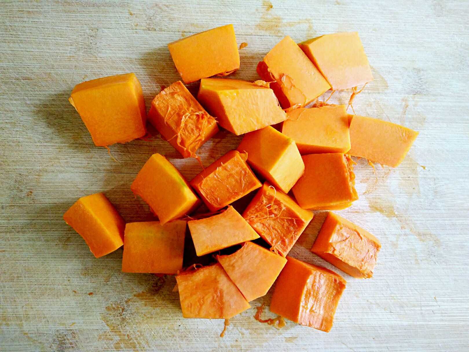 家庭厨房制作场景：大理石台面上摆放玻璃碗装新鲜蒸熟南瓜泥（橙黄细腻）、小罐无盐黄油、全脂牛奶及肉桂棒，手部特写正在用叉子将热南瓜泥与融化的黄油充分拌合，升腾淡淡白色蒸汽