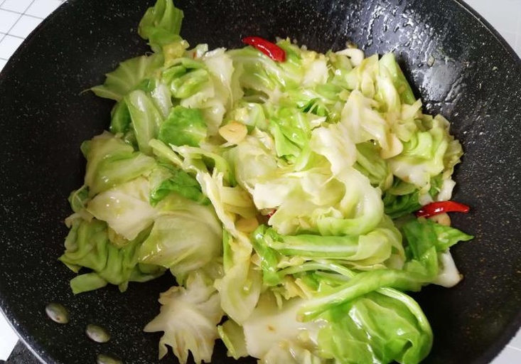 高清特写:刚出锅的呛炒包菜盛于黑陶锅中,展现极致翠绿色泽、均匀油润质感、分明菜丝形态,及升腾的‘锅气’热雾,突出视觉冲击力与烟火气 呛炒包菜出锅特写:铁锅中堆叠着翠绿油亮的包菜丝,表面泛着琥珀色生抽光泽,隐约可见金黄蒜末与红亮辣椒段,一缕白雾正袅袅升起