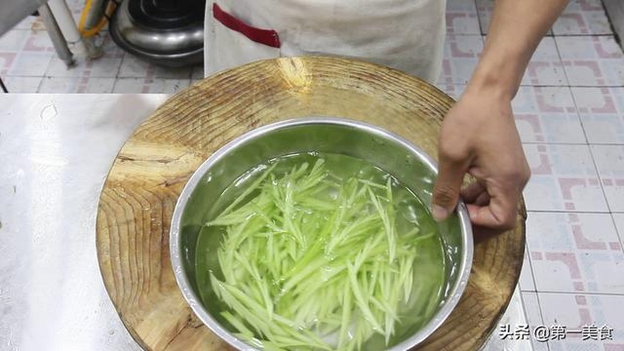 一位厨师正在厨房操作台上将一颗完整的梨子菜用手掰成小朵,旁边放着一碗淡盐水,另一碗已清洗干净的菜花放在滤篮中沥水,背景有计时器显示‘10:00’,体现浸泡过程 梨子菜的清洗与分朵处理过程