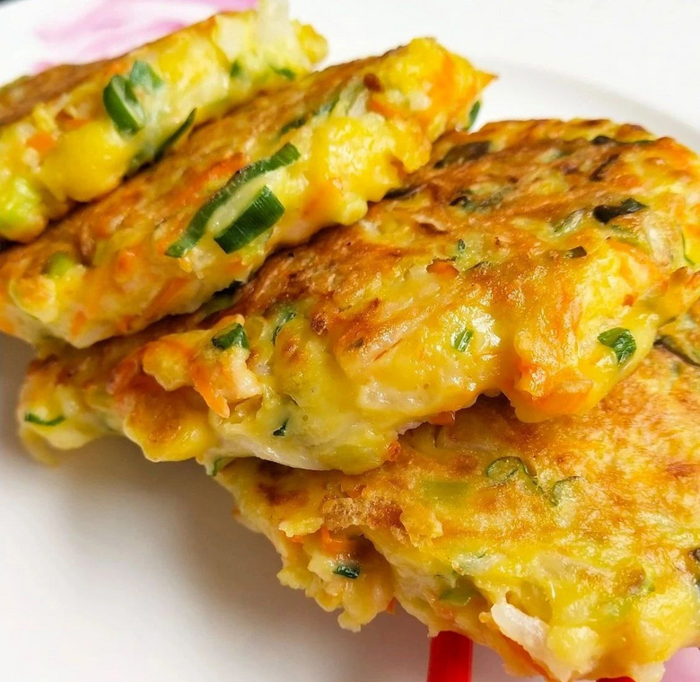 豌豆煎饼特写：金黄色圆形煎饼堆叠摆放，表面微鼓有气孔，撒翠绿葱花，边缘酥脆微翘，切开可见内部豌豆颗粒与柔嫩组织，背景为铸铁煎锅与竹筷