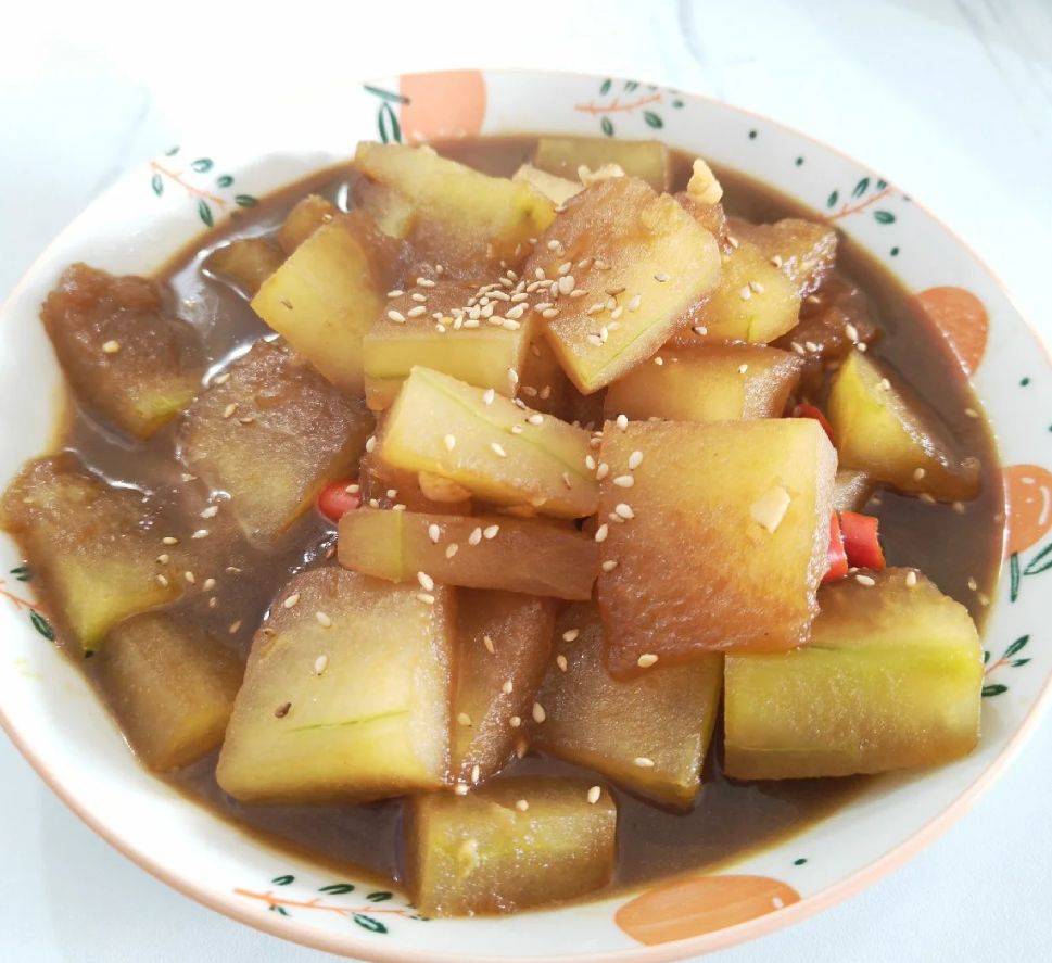 一口黑色铁锅中正盛出刚炒好的一串铃冬瓜,菜色晶莹剔透,冬瓜呈半透明状,表面裹着薄薄一层油亮酱汁,点缀着金黄蒜末和红色干辣椒段,热气腾腾,旁边配有白色瓷盘和木铲,展现家庭厨房的真实烹饪场景 清炒一串铃冬瓜出锅瞬间