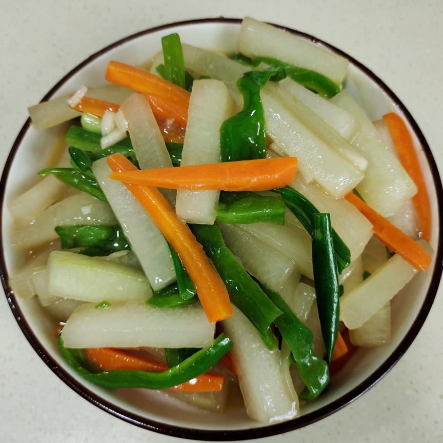 一盘刚出锅的清炒青萝卜丝与青椒片混合菜肴,颜色清新,萝卜丝细长均匀,青椒保持翠绿脆嫩状态,盛放在白色瓷盘中,背景为简约中式餐桌 家常清炒青萝卜丝配青椒片成品图