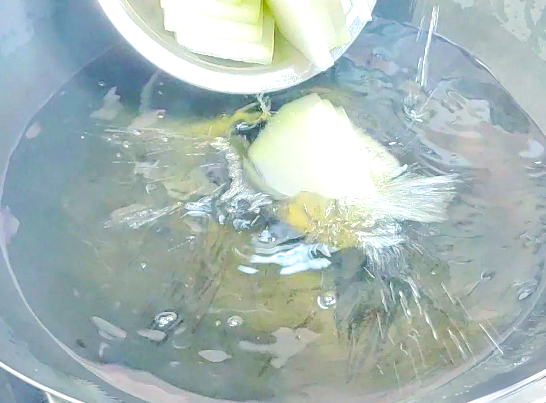 一口不锈钢锅中清水翻滚,菜花小朵正在沸水中焯烫,水面漂浮着少量白色泡沫,锅边可见蒸汽升腾,旁边放有计时器显示时间为2分30秒 菜花在沸水中焯烫的过程