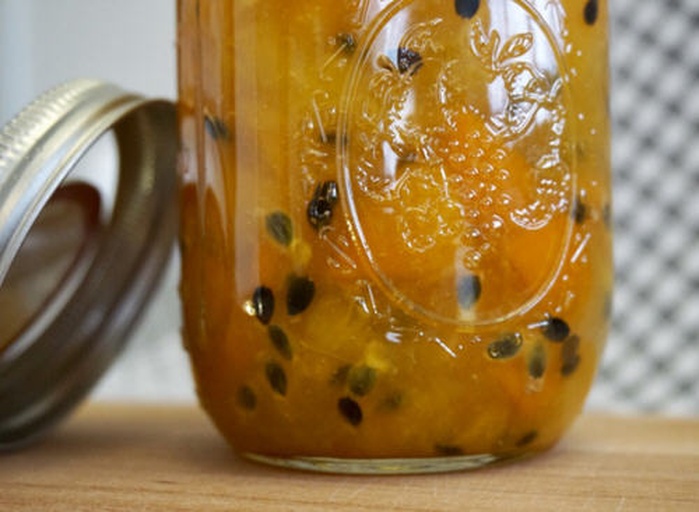 一个透明玻璃罐内装有金黄色的鸭梨果酱,质地细腻有光泽,旁边摆放着一片涂满果酱的全麦面包,背景为白色瓷砖厨房墙面,光线柔和,突出食物的自然美感 玻璃罐中盛放着自制的鸭梨果酱