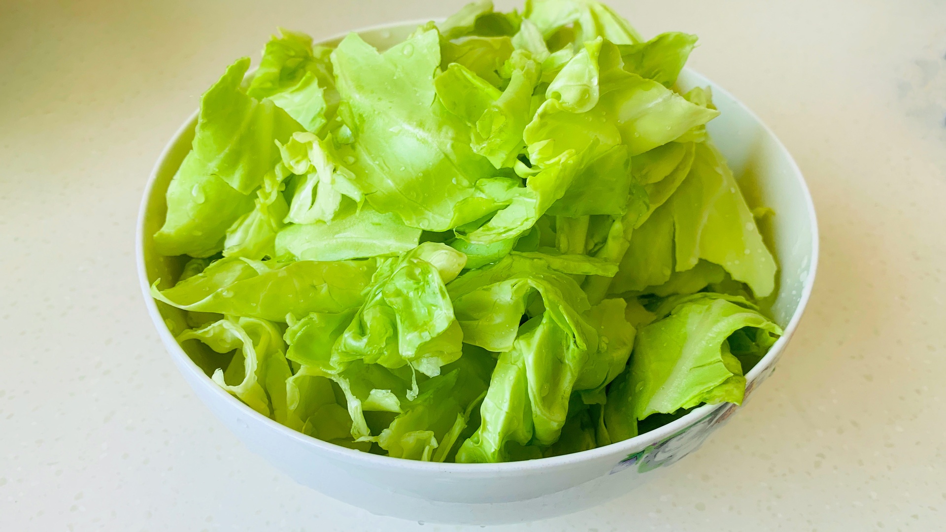 厨师正在将新鲜狼牙生菜加入沙拉碗中