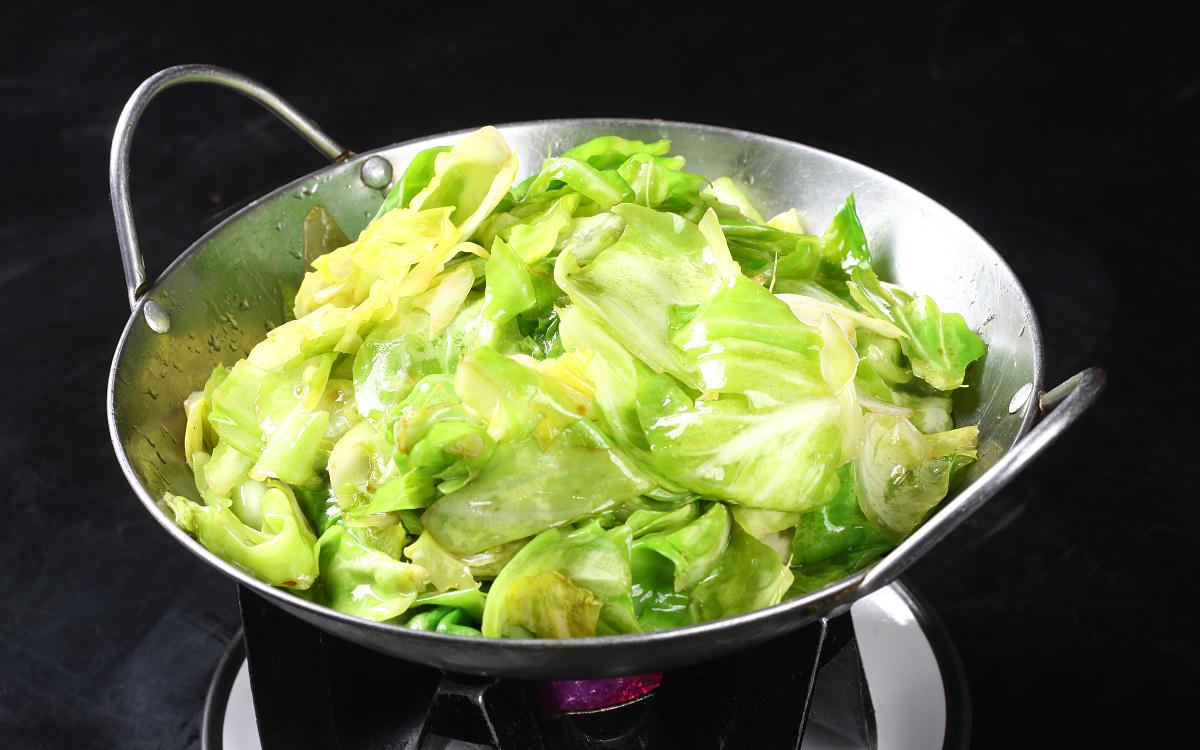 家庭厨房中正在炒制卷心菜的场景