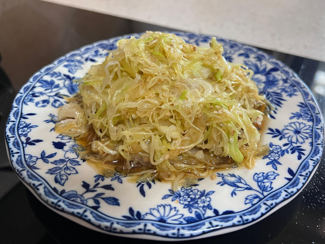 青花瓷盘中盛放着刚出锅的八爪鱼炒韭菜,八爪鱼呈琥珀色,韭菜碧绿油亮,表面泛着光泽,有轻微烟熏痕迹,体现大火快炒的‘锅气’效果 八爪鱼炒韭菜成品特写