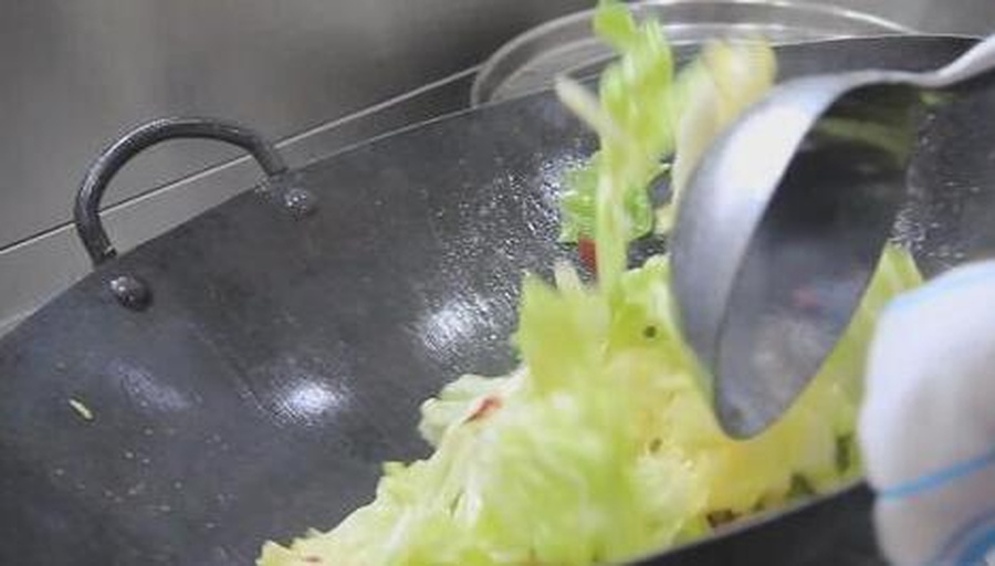 厨房中正在翻炒苦瓜芹菜的过程