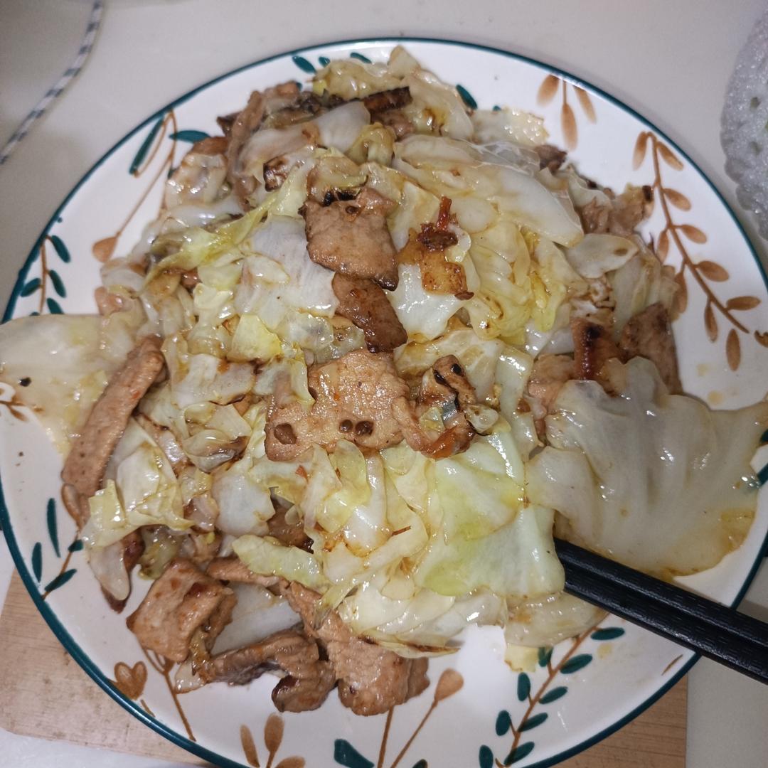 一锅热气腾腾的白菜干炖五花肉盛在粗瓷碗中，汤汁浓稠，五花肉油亮诱人，旁边配有米饭和筷子