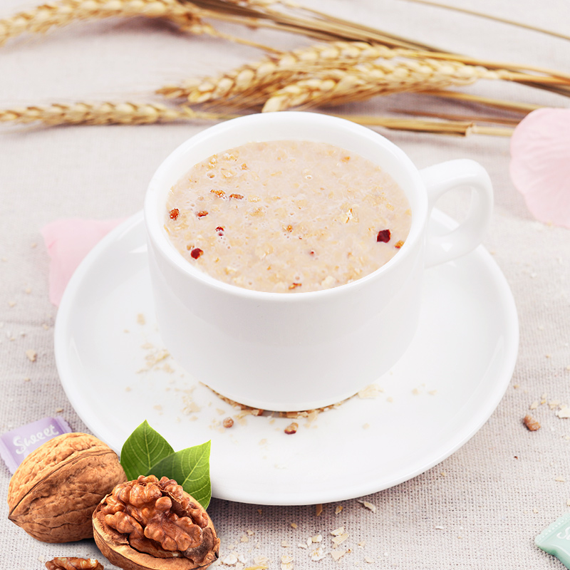 一碗燕麦粥旁边摆放着掰开的两半核桃仁,旁边有蓝莓和蜂蜜壶,整体呈暖色调自然光拍摄,体现健康饮食氛围 健康早餐搭配核桃的摆拍图