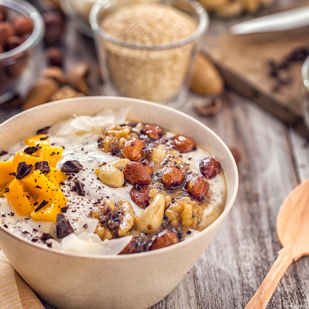 玻璃杯中盛放着由花牛苹果罐头与酸奶、坚果混合而成的早餐碗，色彩丰富，健康感十足
