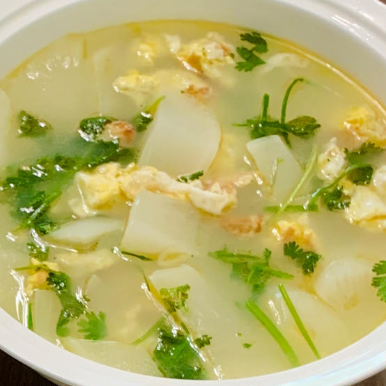 一碗热气腾腾的沙白冬瓜汤特写,汤色清亮微乳白,碗中央是几块晶莹剔透的冬瓜,周围分布着张开的沙白贝,露出橙红贝柱,点缀少许葱花,背景为原木餐桌与竹筷,整体呈现温馨家常氛围 成品沙白冬瓜汤盛在瓷碗中