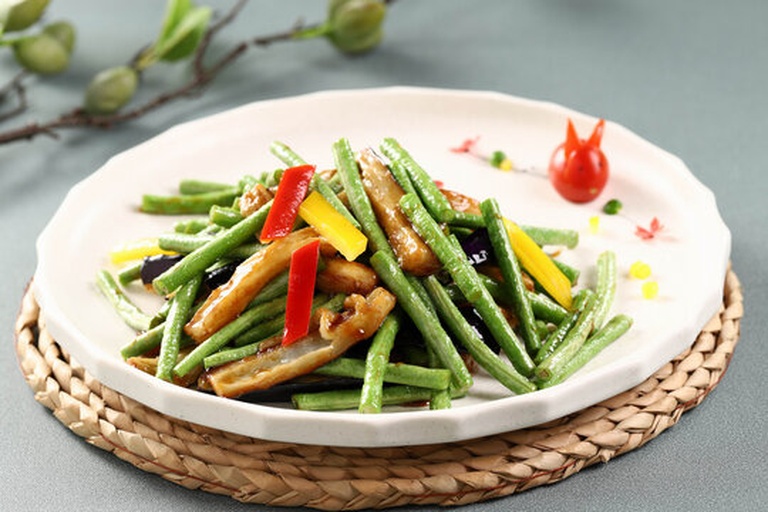 一盘热腾腾的家常炒菜,绿色无筋豆与浅黄色豆筋条交错分布,点缀红椒丝,盛于白色瓷盘中,背景为简约中式厨房环境 无筋豆与豆筋搭配炒菜成品图