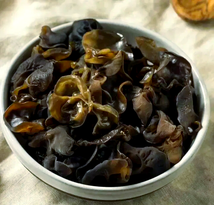 黑木耳山药排骨汤特写:突出汤色清亮、食材形态完整、无浑浊沉淀,体现‘最后12分钟下木耳’的精准火候成果 黑木耳山药排骨汤成品图:浅褐色清汤中浮着琥珀色山药块、墨玉般卷曲黑木耳、淡粉色排骨,枸杞如红宝石点缀,盛于青花瓷汤碗,汤面平静无油星