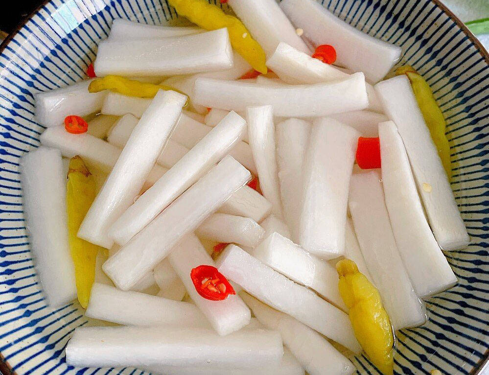 一盘装在小碗中的柠檬泡椒萝卜,旁边搭配柠檬片与泡椒点缀 柠檬泡椒萝卜装盘图