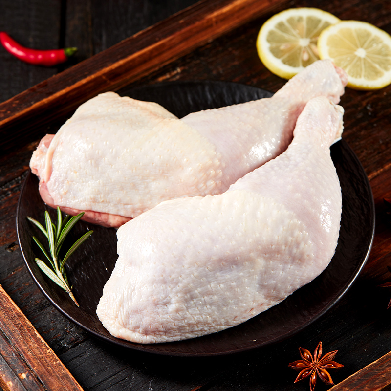 一只新鲜鸡腿被放在白色瓷盘中,旁边有生姜片、葱段和料酒瓶。鸡腿表面已划好刀口,正在倒入冷水锅准备焯水,锅边已有少量浮沫出现 鸡腿清洗与焯水过程