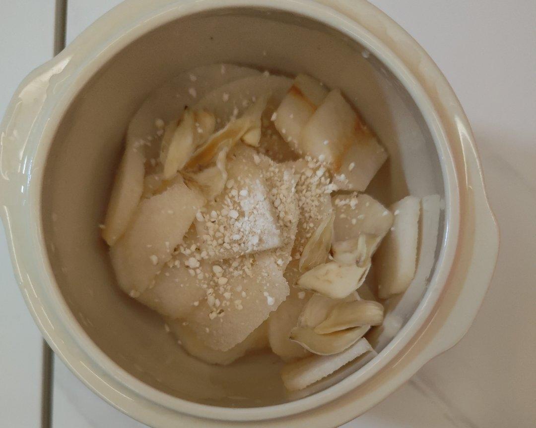 一口深色陶瓷砂锅正在炉灶上慢炖,锅内骨头翻滚,汤汁呈乳白色,旁边摆放着姜片、葱段和几片干燥的白芷药材 砂锅炖骨头过程图