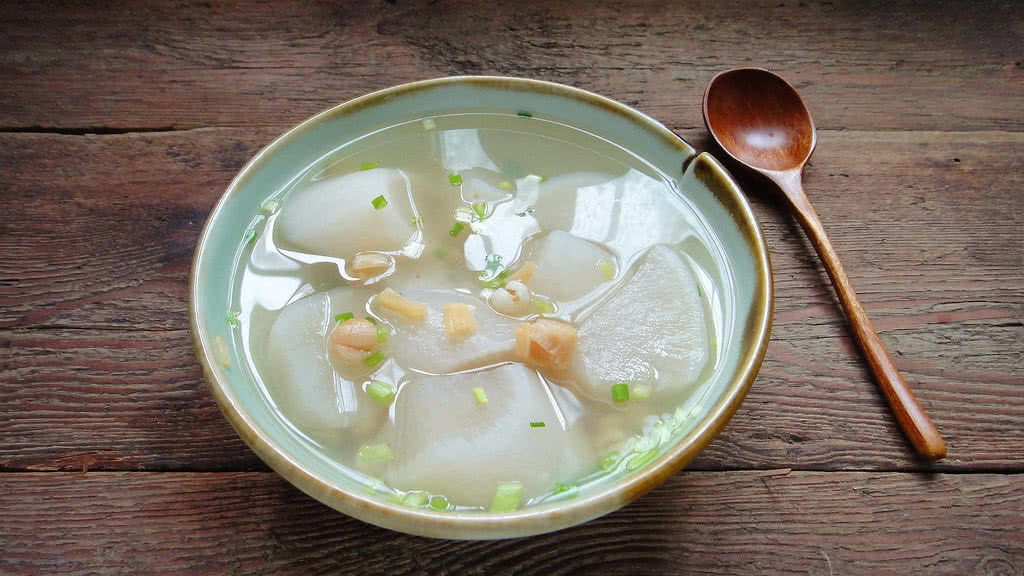 一张木质餐桌上摆放着刚出锅的水果萝卜馅饼,表面金黄微焦,切开可见内部淡粉色萝卜馅料,旁边配有小碟蘸料和绿叶装饰,整体风格温馨自然 水果萝卜馅饼成品展示