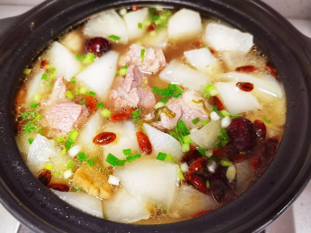 一碗热气腾腾的红皮萝卜煲汤,汤色清澈,红皮萝卜与猪骨清晰可见,旁边点缀着枸杞与红枣 红皮萝卜煲汤成品图