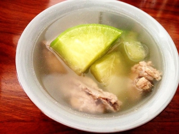 两道装盘精美的菜肴,左侧为白皮冬瓜排骨汤,汤色清澈,冬瓜块呈半透明状,入口即化;右侧为黑冬瓜炖鸭,冬瓜块保持完整形状,汤色微黄,质地紧实。餐具为白色瓷碗,背景为中式餐厅环境 冬瓜菜肴成品对比图