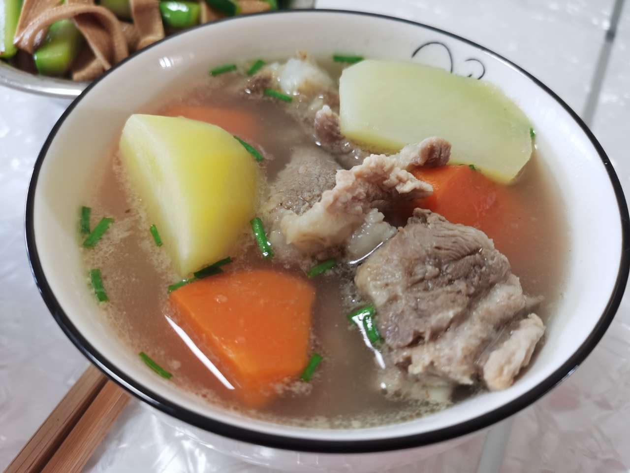 一碗色彩丰富的蔬菜炖胡萝卜，配有土豆、洋葱和少量肉类