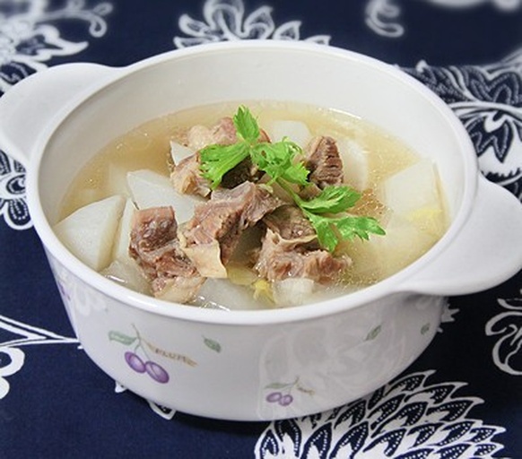 羊肉炖青萝卜成品特写：砂锅中汤色清亮微黄，羊肉块呈琥珀色、纹理清晰不碎，青萝卜块翠绿饱满、半透明状，表面浮着细小油星与葱花，蒸汽氤氲