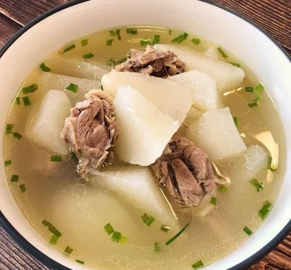 一间温馨的餐厅内,一家三口围坐在木桌旁,桌上摆着一锅热气腾腾的羊肉萝卜汤,汤色乳白,萝卜与羊肉分明可见,孩子正开心地用勺子舀汤,父母微笑注视,氛围温暖幸福 一家人围坐在餐桌前享用热气腾腾的羊肉萝卜汤