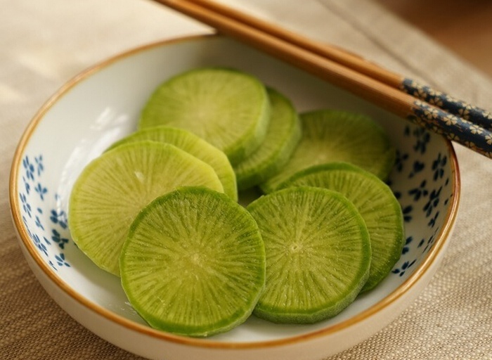 新鲜青萝卜被擦成细丝后放入碗中,撒上白色食盐颗粒,正在腌制出水;旁边放置一块干净的纱布用于后续挤压去水 青萝卜丝杀水过程