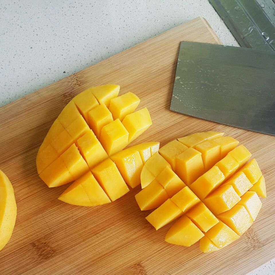 一位厨师戴着黑色防滑橡胶手套,手持一把银色短柄水果刀,站在木质砧板前,面前是一个完整的金黄色金枕头榴莲,背景为明亮厨房,光线充足,突出操作前的准备工作 手持厚手套和水果刀站在砧板前准备切开金枕头榴莲