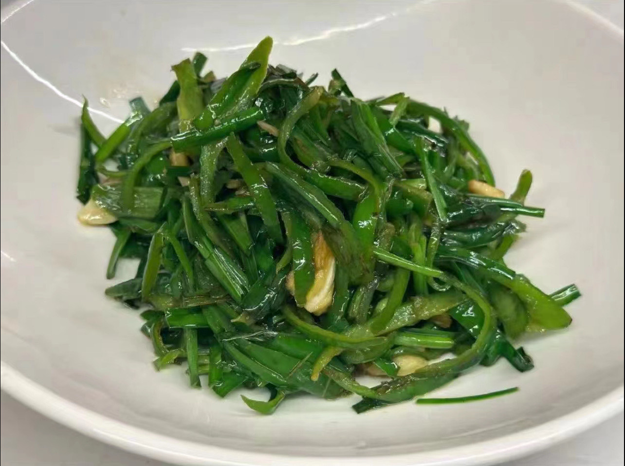 处理好的韭菜和线椒整齐摆放在案板上，颜色鲜亮，准备下锅
