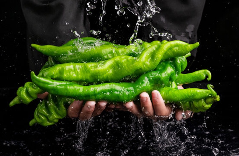 一位厨师正在不锈钢盆中用清水冲洗成串的新鲜青提,青提表面光亮无损,水中泛起细小泡沫,背景为厨房操作台,旁边摆放着剪刀和消毒喷雾瓶 清洗青提