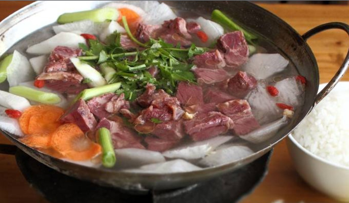 展示新鲜羊肉正在炖煮的画面,锅中汤汁浓郁,搭配胡萝卜、香料等辅料,营造出温馨的厨房氛围 新鲜羊肉烹饪场景图