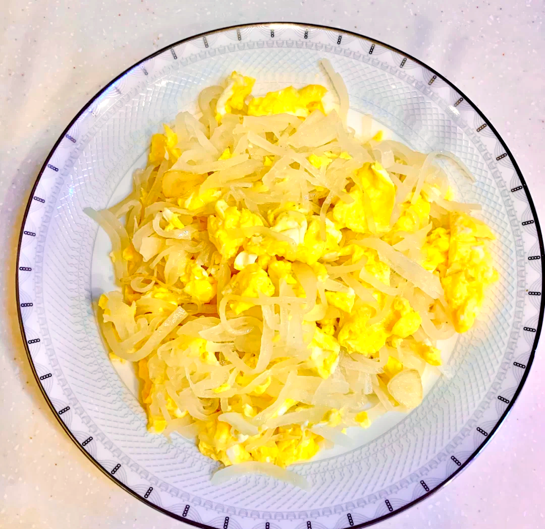 一盘色泽金黄的大葱炒鸡蛋,鸡蛋嫩滑,大葱翠绿,盛放在白色盘中,背景为家庭餐桌 大葱炒鸡蛋成品图