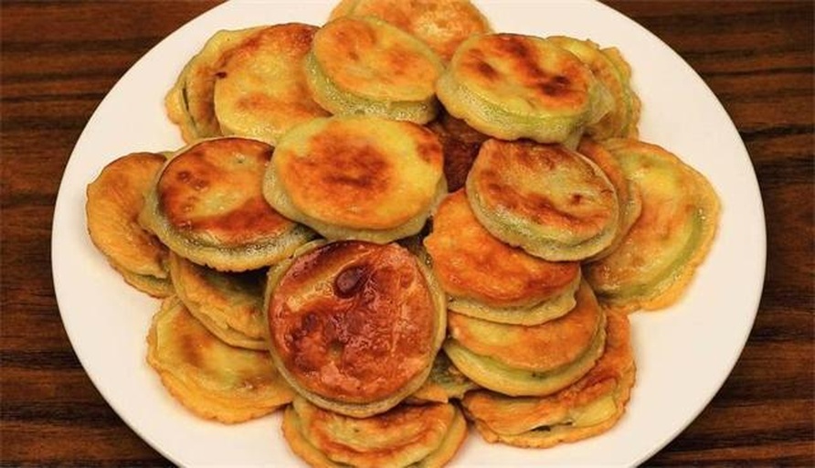 现煎奶油南瓜饼高清特写,展示金黄酥脆表皮、湿润细腻内瓤、自然糯米拉丝结构,摆于竹编盘中,撒少许熟白芝麻点缀 刚出锅的奶油南瓜饼特写:表面金黄带浅褐斑,边缘微翘显酥脆,截面呈现细腻橙黄组织与隐约糯米拉丝