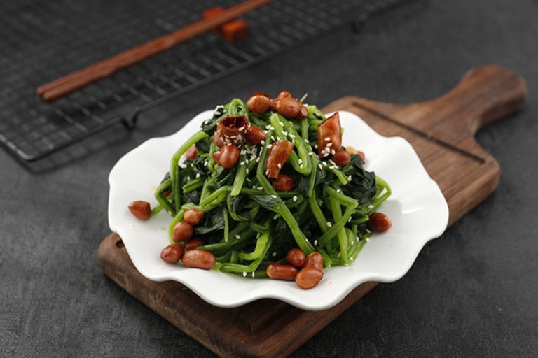 高清微距摄影:芝麻酱拌菠菜成品图,突出芝麻酱与菠菜叶片的物理包裹状态及油润光泽,体现‘覆盖式增效’特征 芝麻酱拌菠菜特写:深绿色菠菜叶上均匀裹覆棕褐色细腻芝麻酱,表面撒少量整粒白芝麻,盘底可见微量琥珀色芝麻油光泽