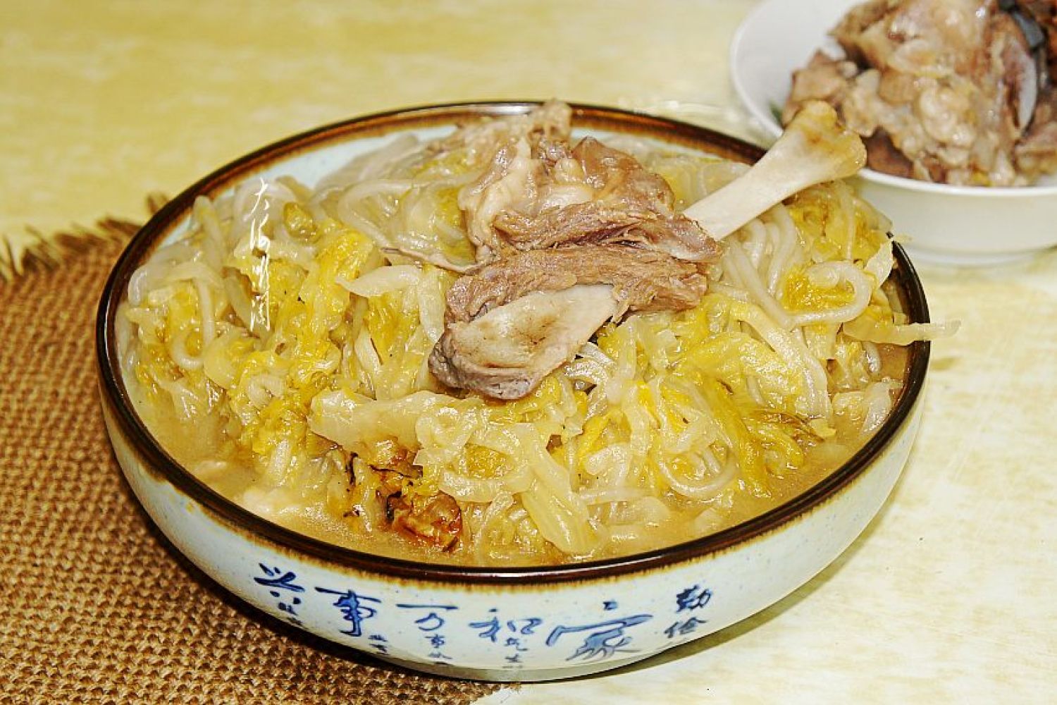 生活化场景图:北方传统白菜炖五花肉烹饪过程,突出'寒温配伍'智慧——白菜微寒配伍五花肉之温,生姜之辛散,实现性味平衡,汤汁澄澈体现寒性食材清热不浊的特质 冬季厨房场景:砂锅中炖煮白菜五花肉,汤色清亮微乳,白菜叶片舒展半透明,五花肉脂边晶莹,灶台旁摆放新鲜大白菜与生姜片