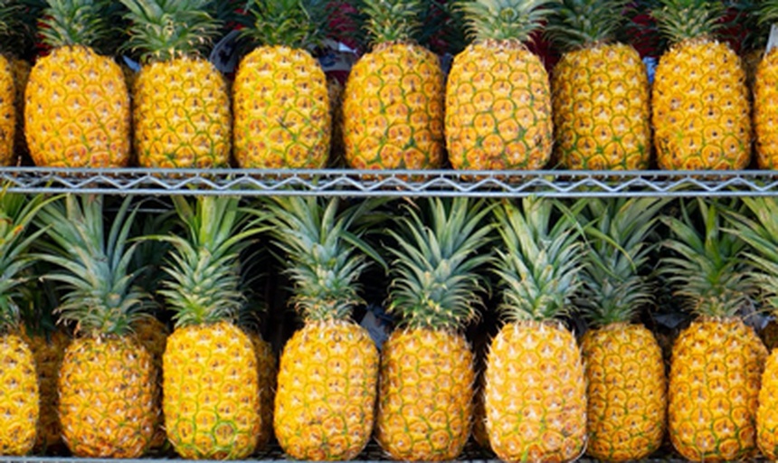 超市生鲜区货架上摆放着不同形态的菠萝产品:左侧为带叶的新鲜菠萝,中间为透明包装的切块果肉,右侧为标有‘菠萝干’的独立小包装零食和金属罐头,背景有‘热带水果’标识牌 超市货架上陈列的多种菠萝制品,包括新鲜整颗菠萝、真空包装果肉、菠萝干零食和罐头