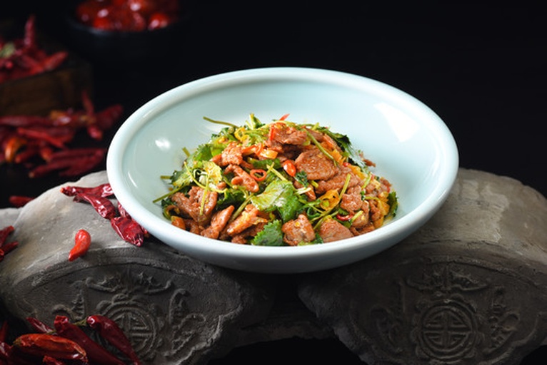 一碗色彩丰富的香菜拌牛肉成品图，红褐色牛肉与翠绿香菜交错，表面泛着油光并点缀白芝麻