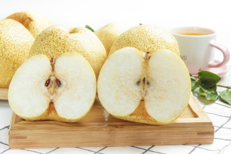 一颗被横向切开的酸梨,露出洁白微泛乳黄的果肉,汁水丰富,纤维细腻可见,刀口处有晶莹水珠滴落,背景为浅灰色粗布纹理,左侧摆放一把不锈钢小刀,整体画面干净清新,突出食材新鲜感 切开的面酸梨横截面特写