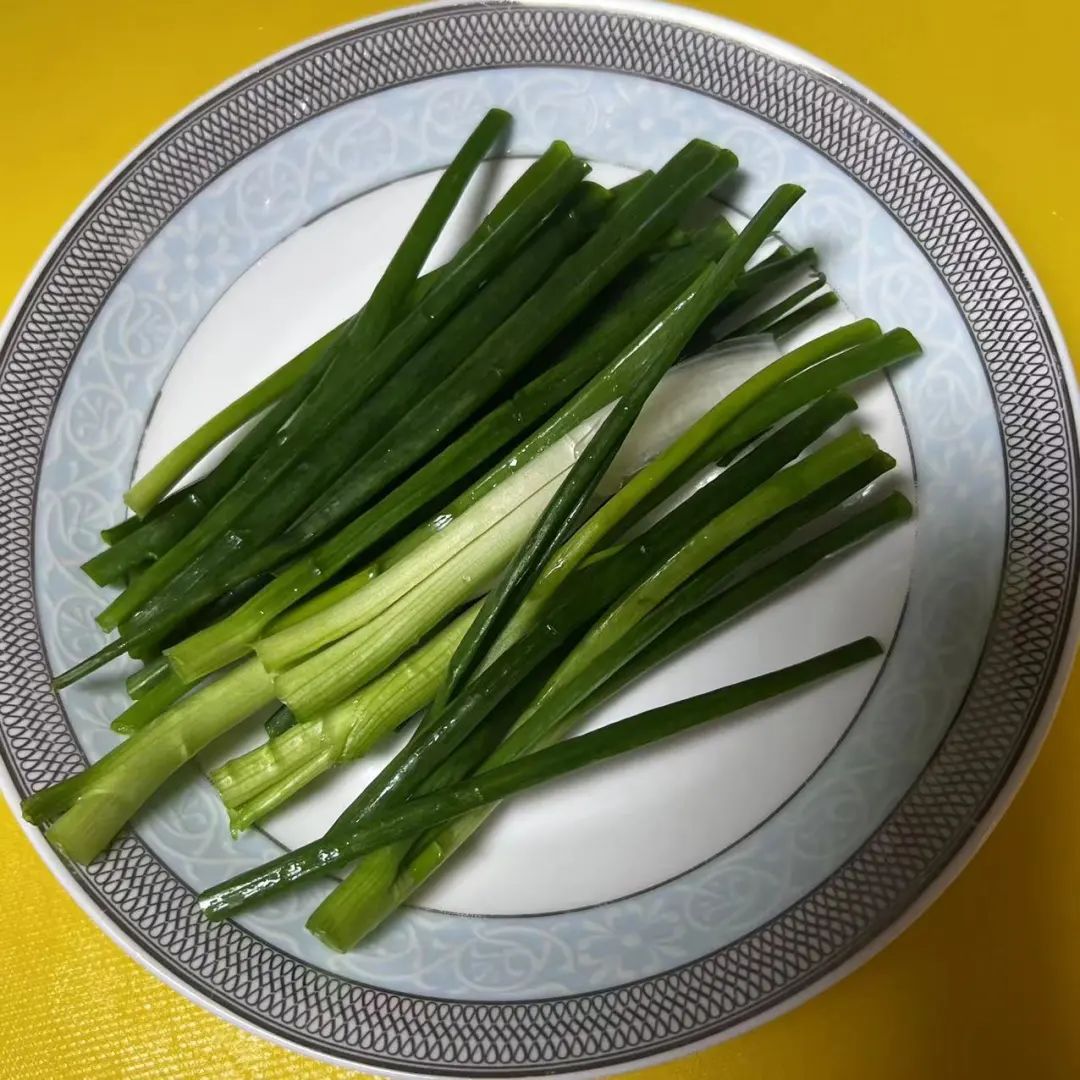 一位厨师正在案板上清洗一根新鲜的章丘大葱,水珠溅起,旁边摆放着已切好的葱段、葱花和葱丝,展示不同切割方式 章丘大葱的清洗与切割过程