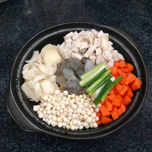 砂锅中荔浦芋头与海参在琥珀色浓汤中缓缓 simmering,表面泛着油光,周围蒸汽升腾,旁边摆放着姜片、葱段和调料瓶 荔浦芋头海参与浓汤共煨过程