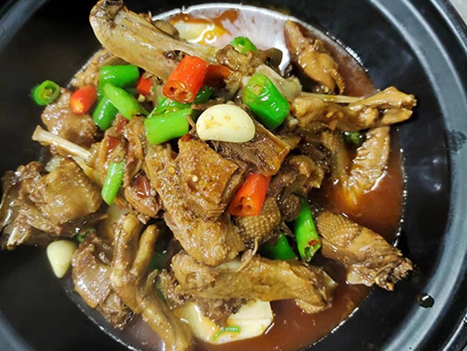 一锅热气腾腾的胡椒炖鸭,汤色乳白浓稠,表面浮着细密油珠和黑色胡椒颗粒,鸭块清晰可见,旁边摆放着白色瓷勺和青花瓷碗,背景为木质餐桌,营造出温暖的农家用餐氛围 胡椒炖鸭成品特写