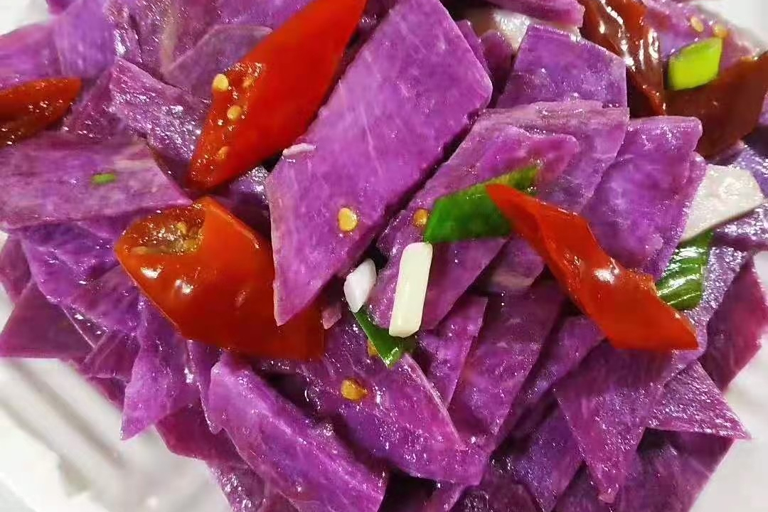 家庭厨房温馨场景：三代同堂围坐餐桌，祖母用竹刀切开刚蒸熟的黄心番薯，金黄薯肉油润软糯，孩子伸手欲接，父亲举手机拍摄，桌上还摆着番薯叶清炒小碟与紫薯酸奶杯