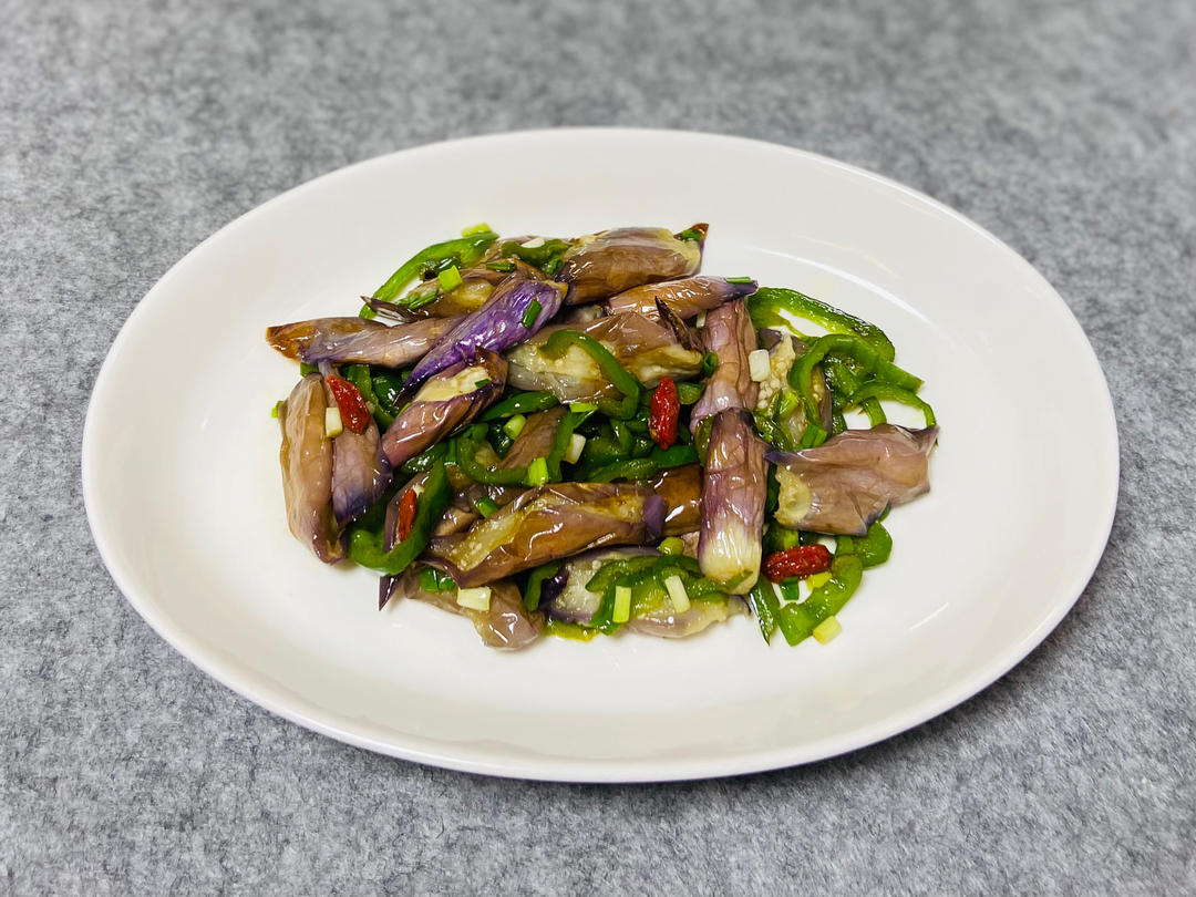 厨师正在灶台前用铁锅翻炒青茄，锅中青茄呈翠绿色，蒜片清晰可见，火焰旺盛，动作利落